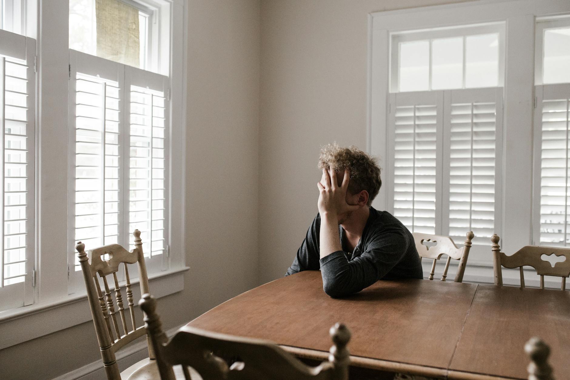 Woman sits at table by herself, staring out the window.